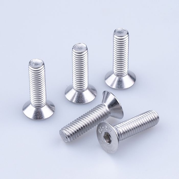 Three stainless countersunk socket screws standing upright, showing the conical head