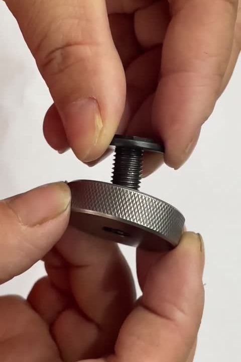 A hand holding a hex screw that has stopped partway into a knurled thread ring gauge